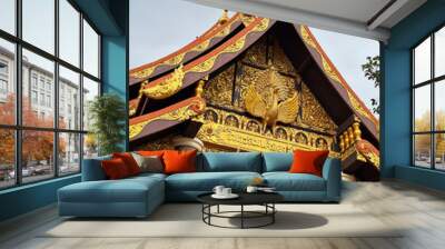 A close-up photo of a traditional Thai temple roof, showcasing intricate carvings and vibrant colors. The roof is adorned with a golden Garuda, a mythical bird, and features a red and gold color schem Wall mural