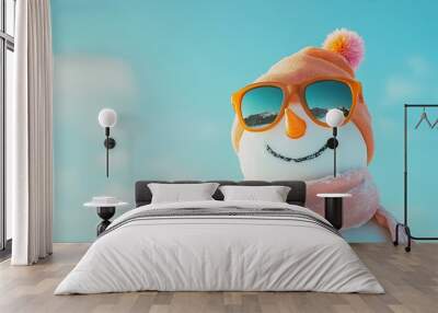 A cheerful snowman wearing sunglasses and an orange hat enjoys a bright winter day under a clear blue sky Wall mural