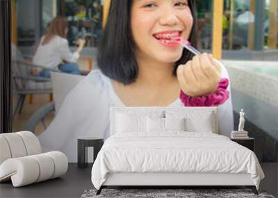 Asian teenager with pink braces on teeth eating red velvet cake Wall mural