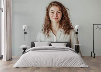 Smiling woman holding a book, light background. Wall mural