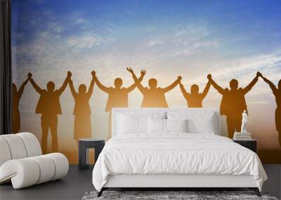 Silhouette of happy business teamwork making high hands over head in sunset sky background for business teamwork concept Wall mural