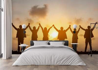 Silhouette of happy business teamwork making high hands over head in sunset sky background for business teamwork concept Wall mural