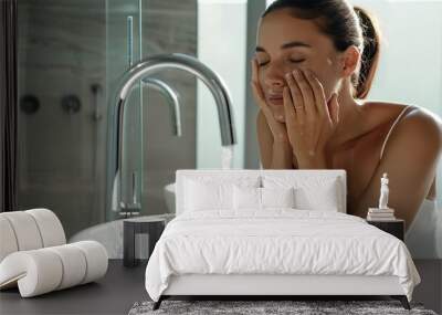 Beautiful woman washing her face in modern bathroom. Image of beautiful girl washing face in the morning. Wall mural