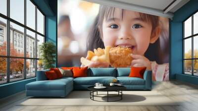 Close up portrait of a satisfied pretty little asian girl eating fried chicken and french fries In the restaurant. Unhealthy food concept. copy space for text. Wall mural