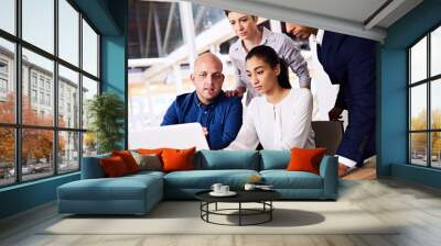 Group of young diverse and dynamic, well dressed architects busy looking over their latest rendering of the site in their major current project in which they are the core team. Wall mural