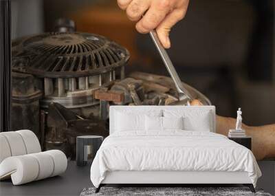 A man repairs the engine of a gasoline lawn mower. Close-up hands holding wrench Wall mural