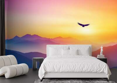 A beautiful silhouette of a bird soaring over majestic mountains at sunrise, capturing the essence of freedom and tranquility. Wall mural