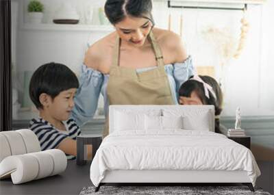 Asian young single mother with son and daughter in kitchen. Enjoy family activity together. Wall mural