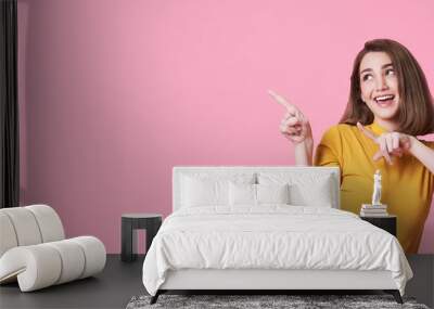 Beautiful healthy young woman smiling with his finger pointing and looking at on light pink banner background with copy space. Wall mural