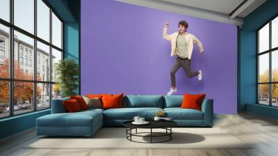 Full length man running jumping in air isolated on purple copy space background. Cool man joyful running in copy space. Studio short. Wall mural