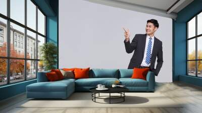 handsome and friendly face asian businessman smile in formal suit points his hands to presented to copy space on white background studio shot. Wall mural