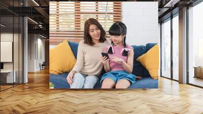 Happy Asian family using smartphone together on sofa at home living room. Wall mural