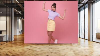 Happy Asian teen woman smiling and walking dance while celebrating success isolated on pink background. Wall mural