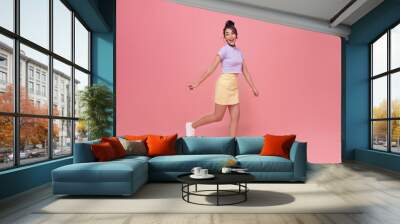 Happy Asian teen woman smiling and walking while looking back isolated on pink background. Wall mural