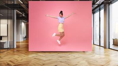 Happy Asian woman smiling and jumping while celebrating success isolated over pink background. Wall mural