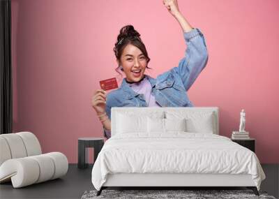 Happy young asian woman showing credit card on pink studio background. Customer girl get satisfied of credit card service with smile on face Wall mural