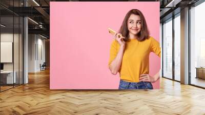 happy young woman celebrating with mobile phone isolated over pink background. Wall mural