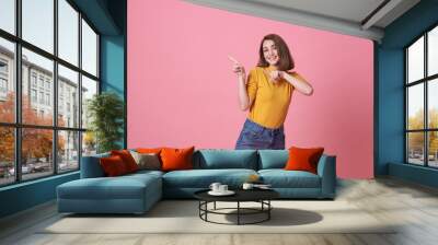 Happy young woman standing with her finger pointing isolated over pink banner background with copy space. Wall mural