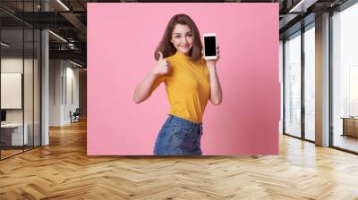 Portrait of happy young woman showing at blank screen mobile phone isolated over pink background. Wall mural