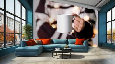 women hand holding white ceramic coffee cup with light decoration. mockup mug for creative advertising text message content. Wall mural