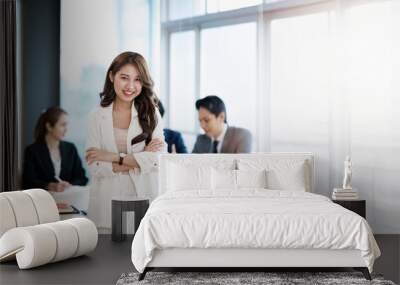 A confidence businesswoman standing with arms crossed and smile at the camera while working and  meeting with colleagues in an office. Wall mural