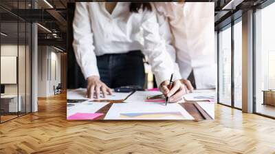 Hands of young businesspeople holding pen and pointing at business graph report  on table Wall mural