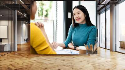 Two young Asian business woman discuss working with new startup project idea presentation analyze plan marketing and investment in the office. Wall mural