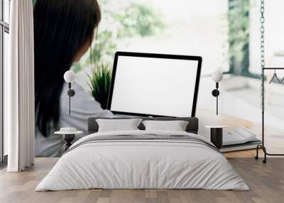 Young businesswoman working on laptop computer at office. Blank screen for graphic design. Wall mural