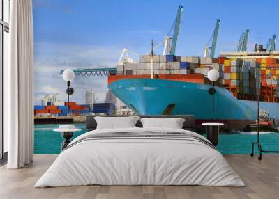 Large cargo ship with many shipping containers sailing from port  Wall mural