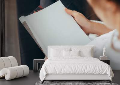 Beautiful female hands hold an open book or magazine in the room Wall mural