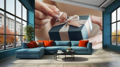 Close-up of female hands holding a small gift wrapped with a satin ribbon Wall mural