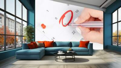 female hand marking with a red pen on a 15th day of the month  calendar circles the day, deadline concept Wall mural