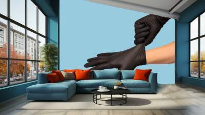 man puts on sterile black gloves on a blue background. Hazard, hygiene, control Wall mural