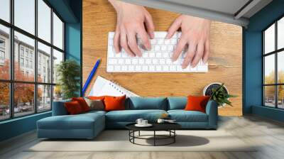 Office worker checks email while sitting at a wooden table. Wall mural