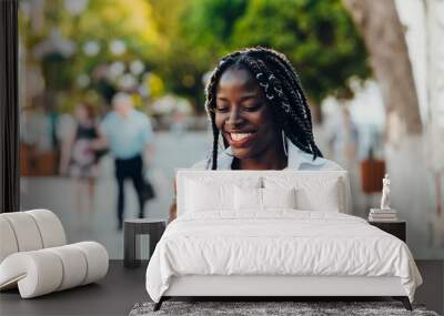 Portrait of a young African American girl with pigtails . The girl is talking on a mobile phone, smiling. Sunny day. Wall mural