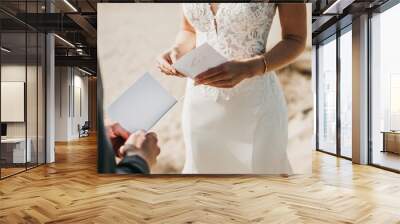 Close Up Of Bride and groom reading wedding vows from paper at wedding ceremony in nature Wall mural