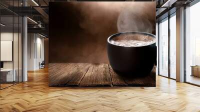 A black cup of frothy hot chocolate resting on a wooden plank with visible texture, steam ri  Wall mural