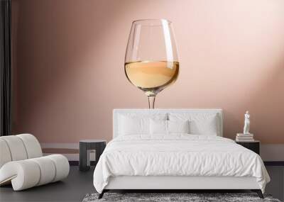 A sleek white wine glass filled with a light golden wine, set against a minimal, light-color Wall mural