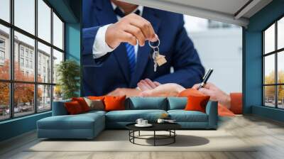  A businessman at a desk in a sales office sells a condo building to a customer. They agree to sign a contract, covering real estate investments in offices, apartments, and commercial properties. Wall mural