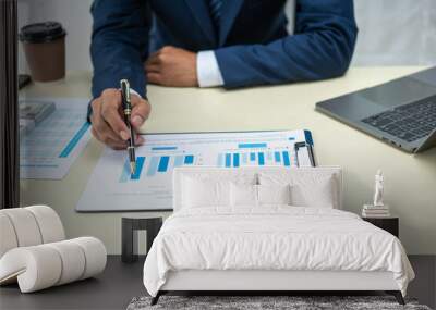 A banker in a suit works at a desk handling loans, analyzing client financial data, providing financial advice, dealing with stocks and the stock market, and studying economic situations. Wall mural