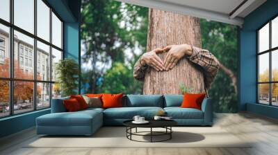 A male hand hugs a tree, symbolizing love for nature and the environment. This act represents the importance of trees in preventing global warming and restoring environmental balance, as seen Wall mural