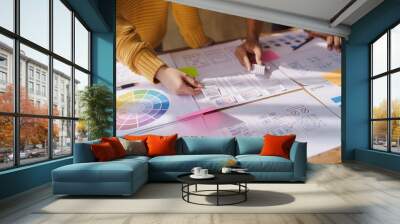 A UX design team is a confluence of user research, UX, UI design with layout paper on desk. Wall mural