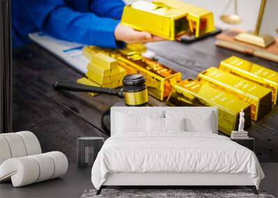 An Asian businesswoman is sitting at her desk in the office, analyzing gold bullion prices, the gold market, government policies, oil prices, inflation, and the potential to invest in digital gold. Wall mural