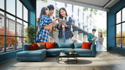 Attractive asian college student using laptop and tablet studying with group of friends together with english language classroom, social media and education concept. Wall mural