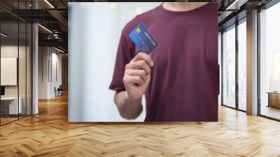 Close-up of a man's hand holding a bank credit card, highlighting online services for lending and access to credit,demonstrating financial convenience and flexibility for secure digital transactions Wall mural