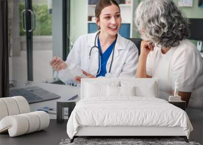 Monthly health check-ups and counseling sessions are provided to an elderly Asian woman by a Caucasian female caregiver, offering support, advice, and motivation. Wall mural