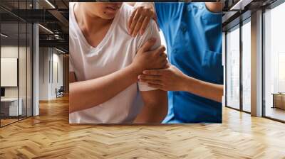 Physical therapist is examining the injured arm, waist and neck muscles of an athletic male patient. Wall mural