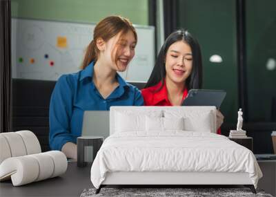 Two Asian business woman work at a desk, discussing business strategies, marketing, plans.They analyze money matters explore how to write a clear, easy-to-understand business plan for future growth Wall mural