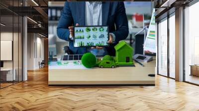 Two Asian businessmen in formal suits discuss ideas and suggestions at an office desk, focusing on green housing estates, city planning, renewable energy, and achieving net zero emissions by 2050. Wall mural