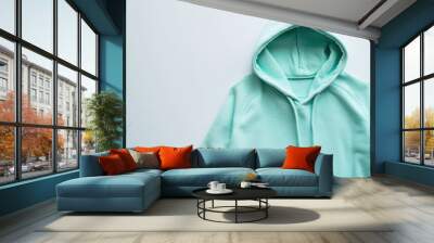 A lightweight women's hoodie jacket in mint green, isolated on a bright white surface, promoting casual and sporty styles Wall mural